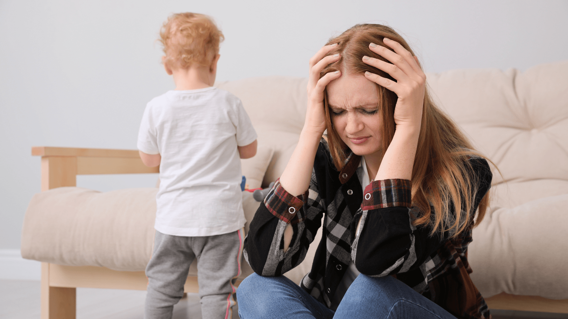 A child playing and A mother holding her head because of stress depicting perripartum depression.