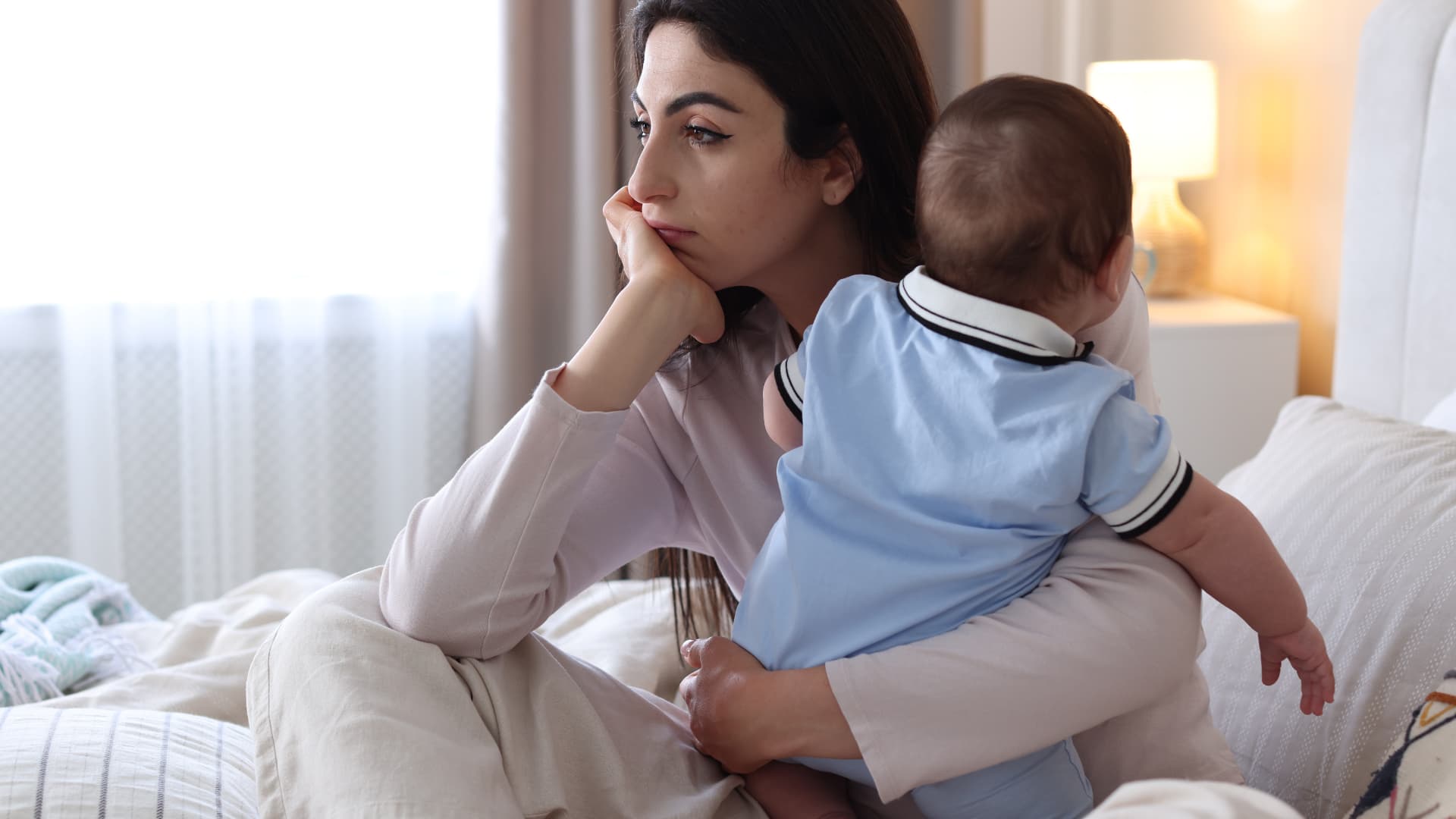 Woman holding baby, looking away