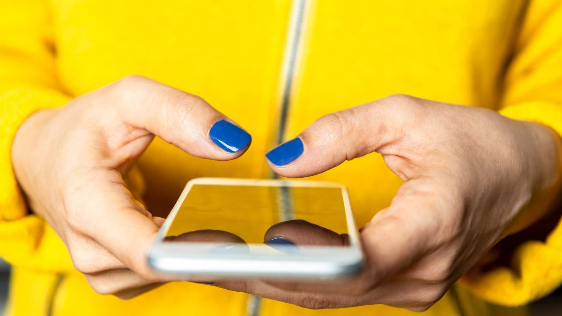 Woman using a mobile phone with blue fingernails