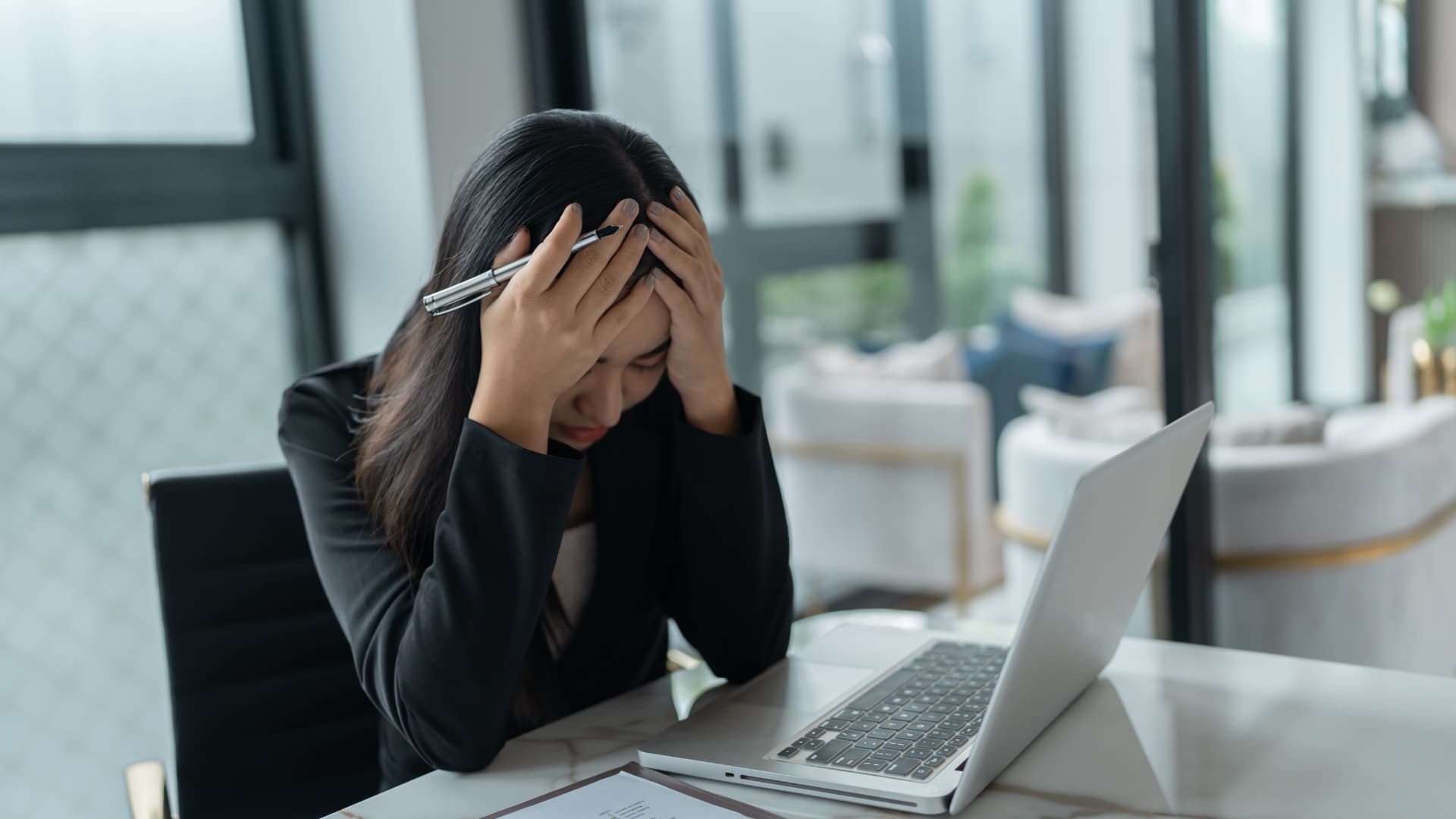 A woman at a desk with her head in her hands in frustration