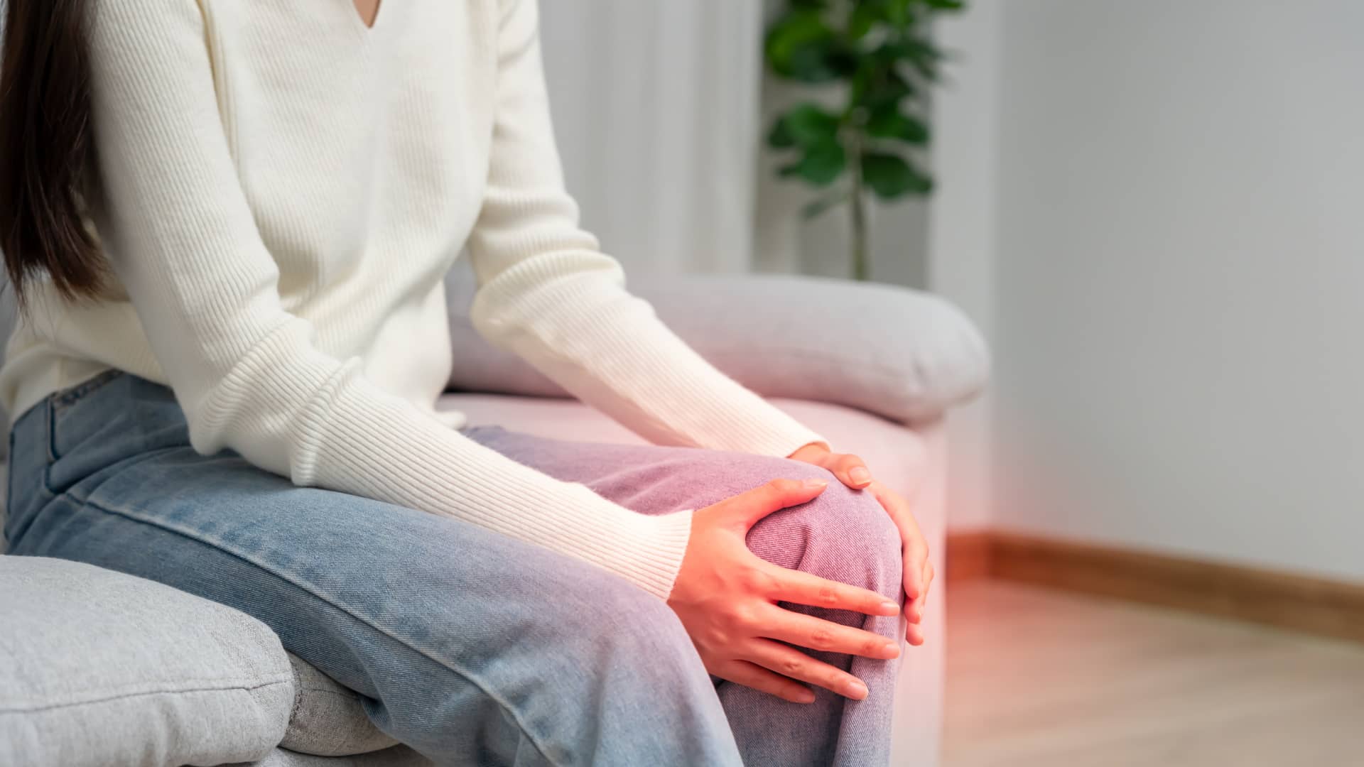 A woman holds her knee in pain