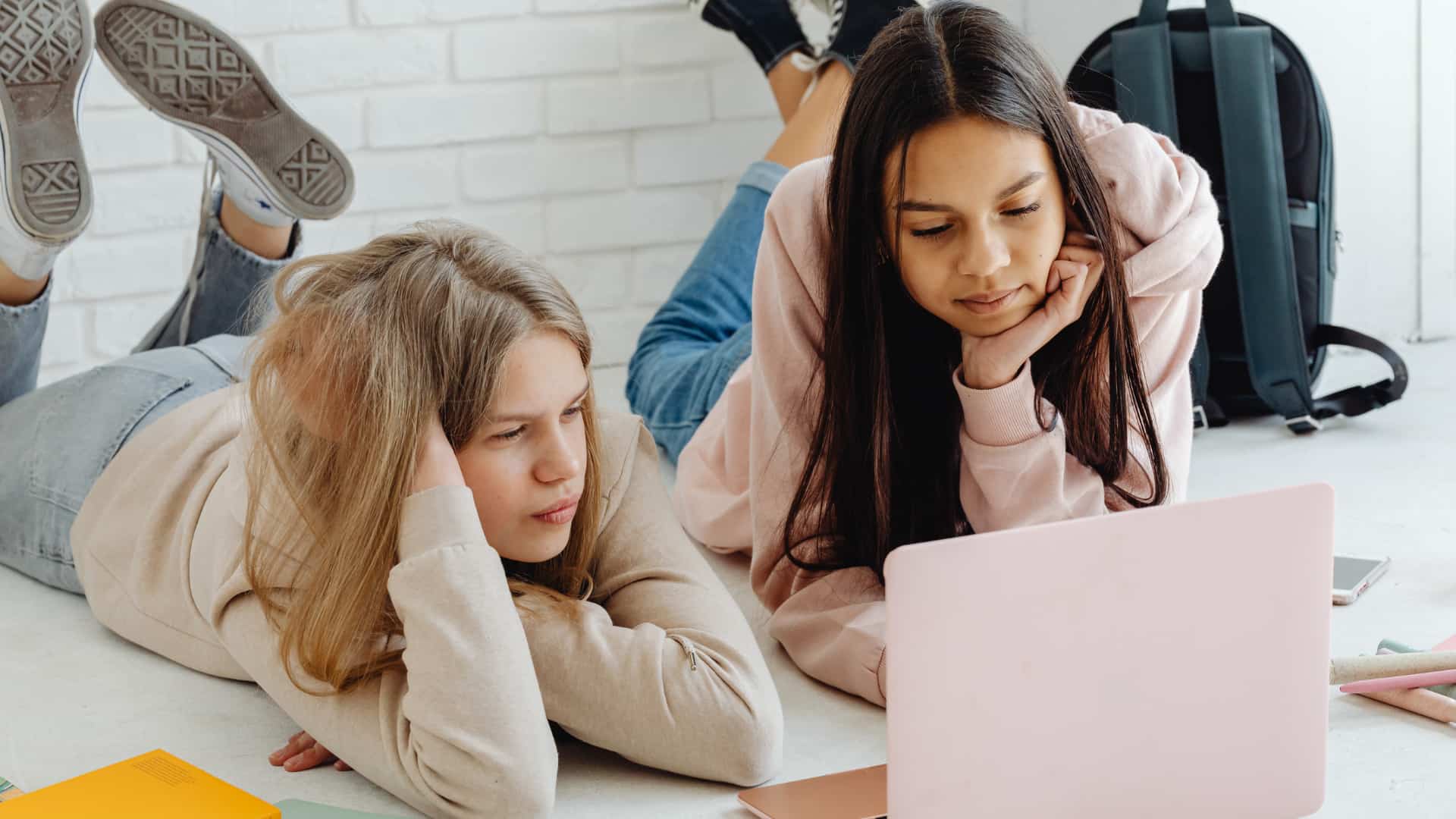 Two girls are intently focused on a laptop screen,
