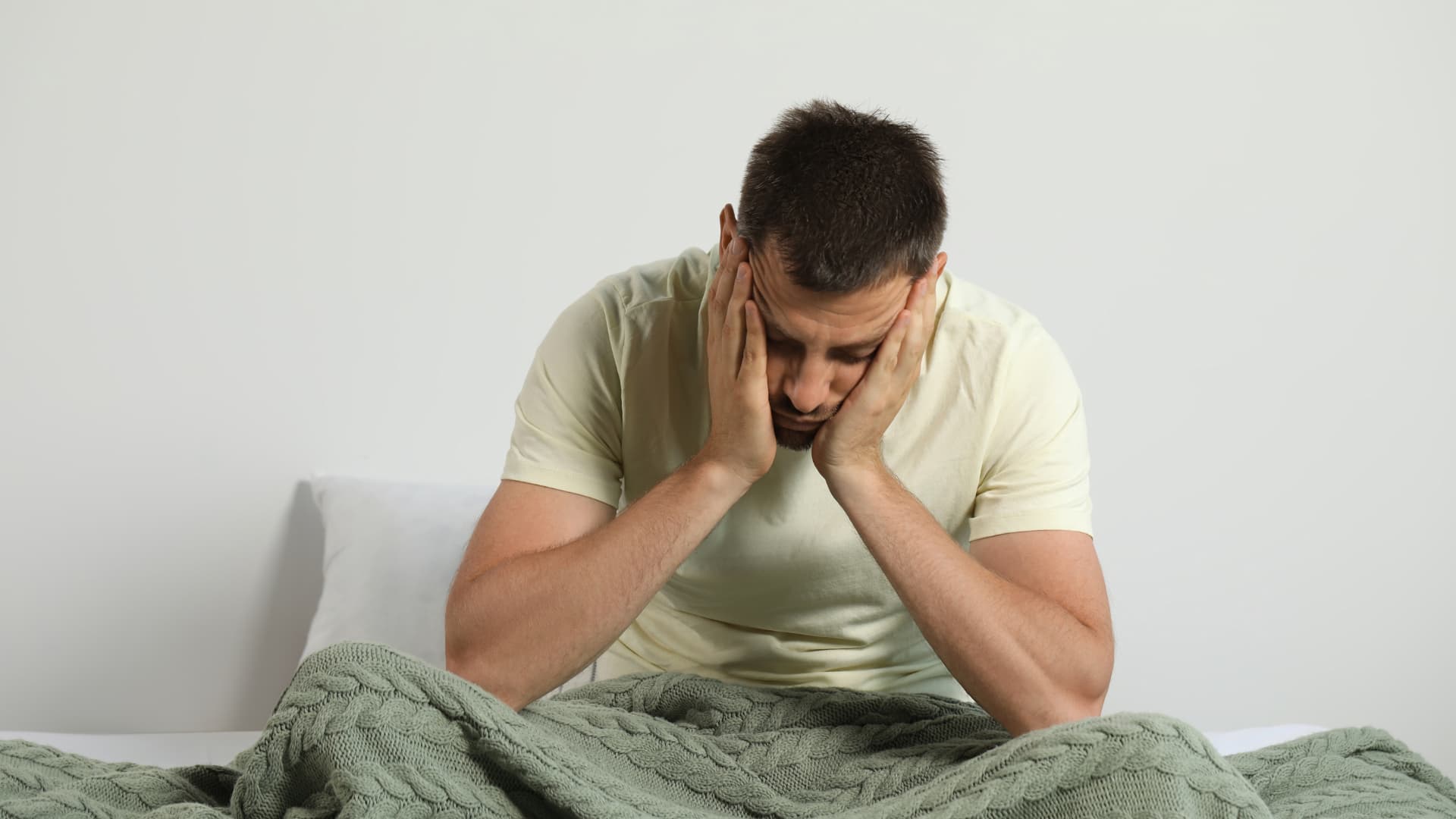 Man holding his head in bed