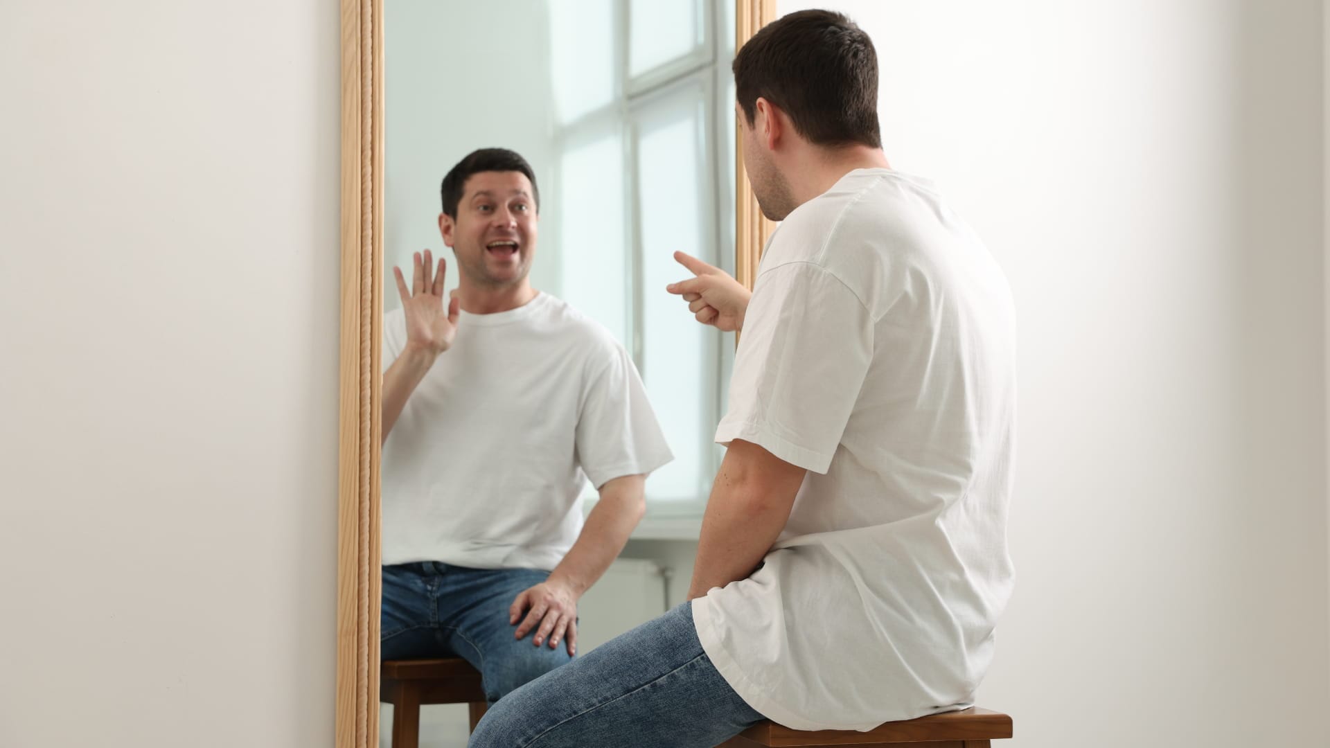 A man sits talking animatedly to his reflection