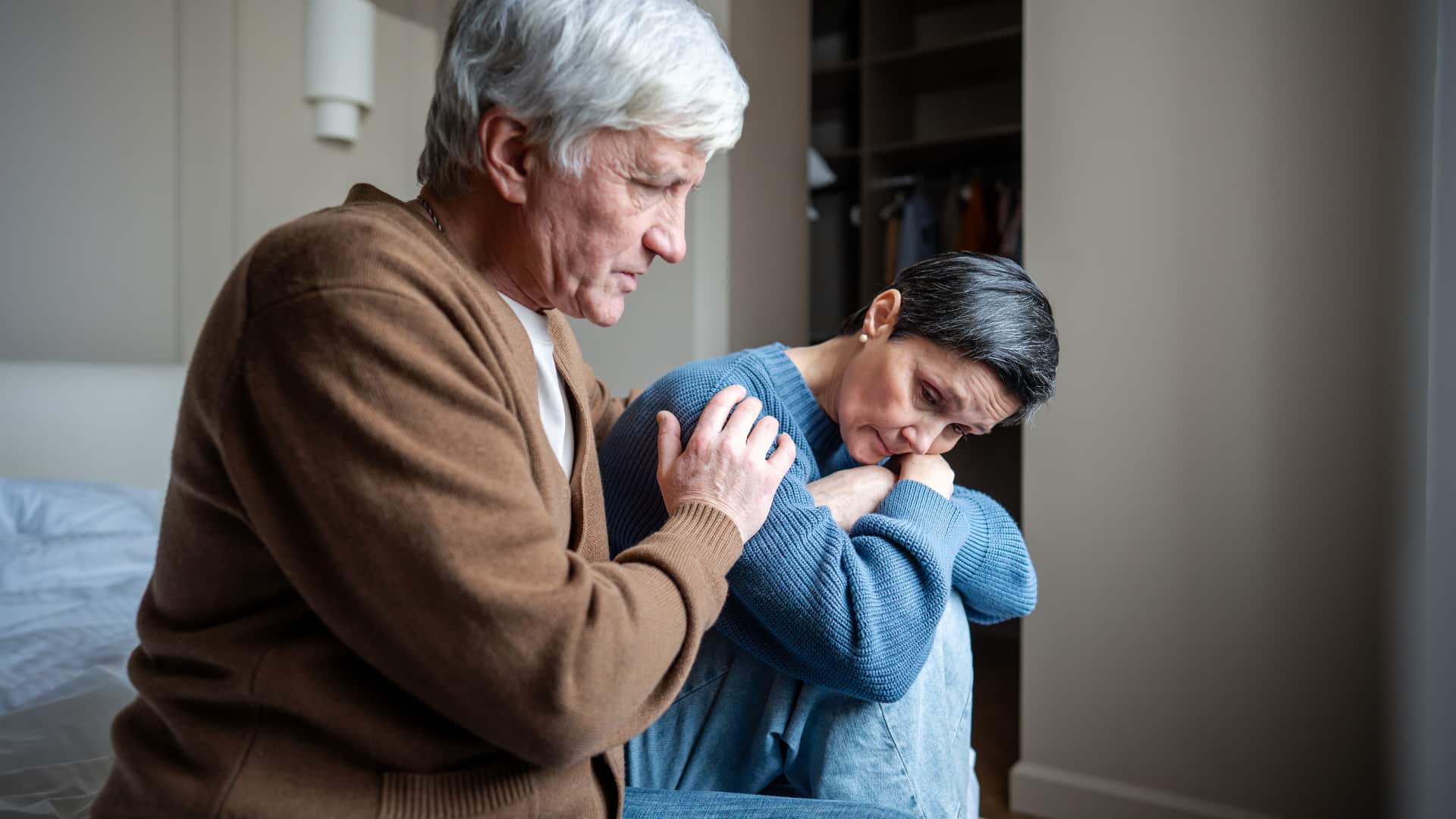 A man puts a hand on a woman's shoulder