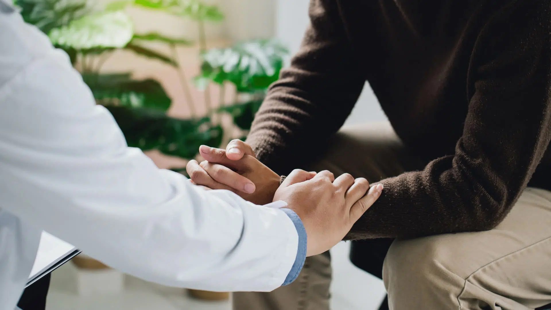 A professional holding the hands of a patient in a gesture of empathy