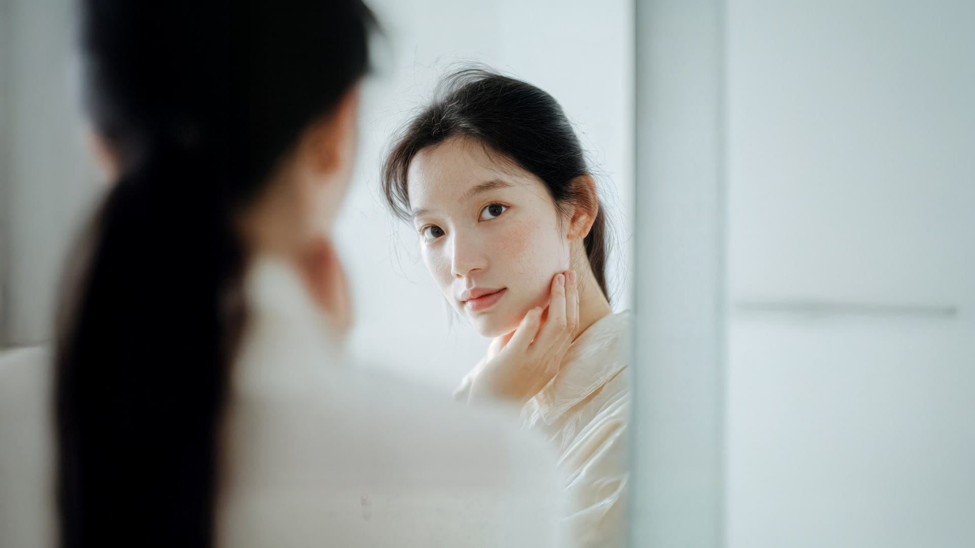 A woman looks intensely at her reflection in the mirror