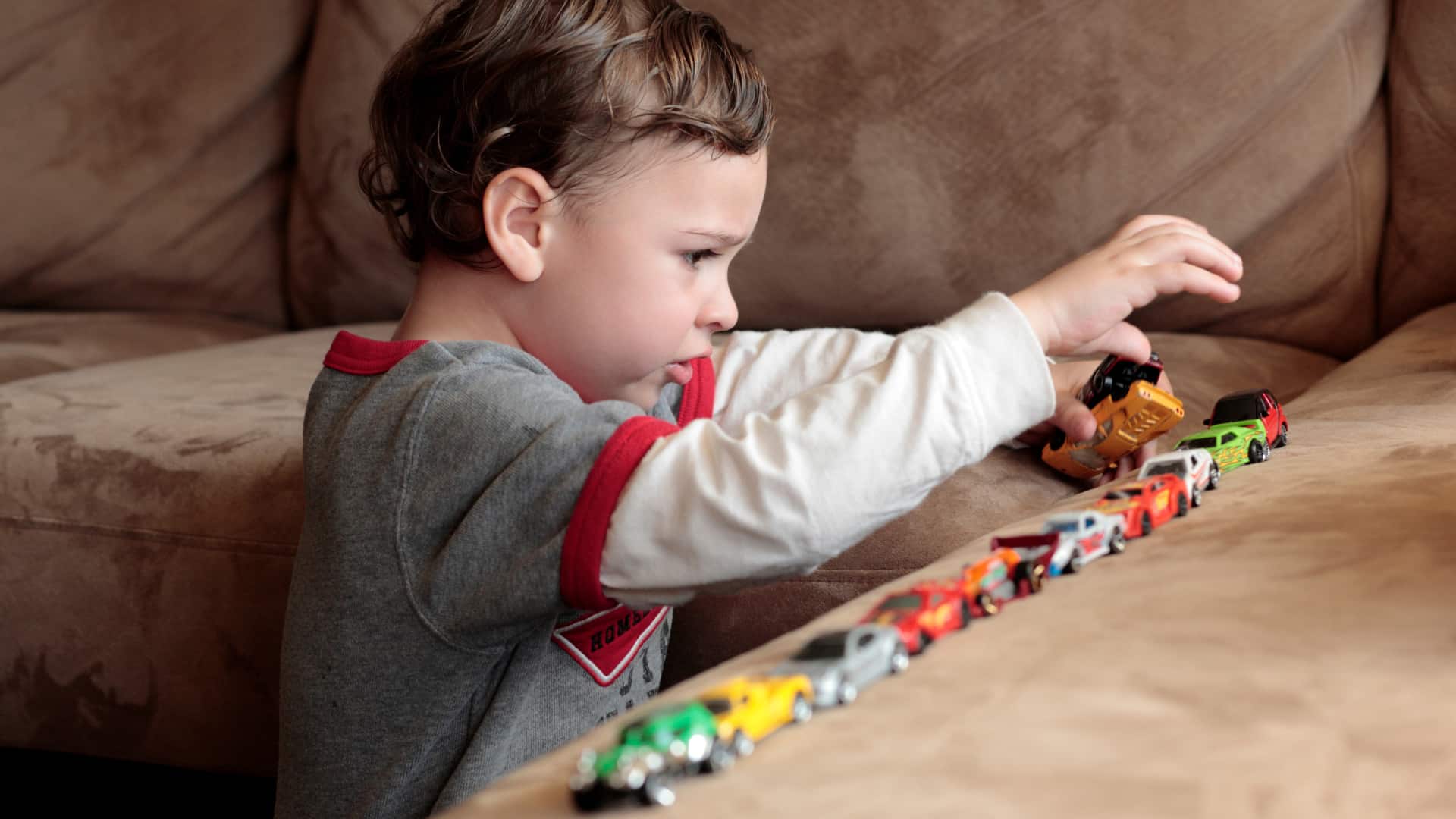 A child making a line with toy cars showing Autism psychiatry in sugarland