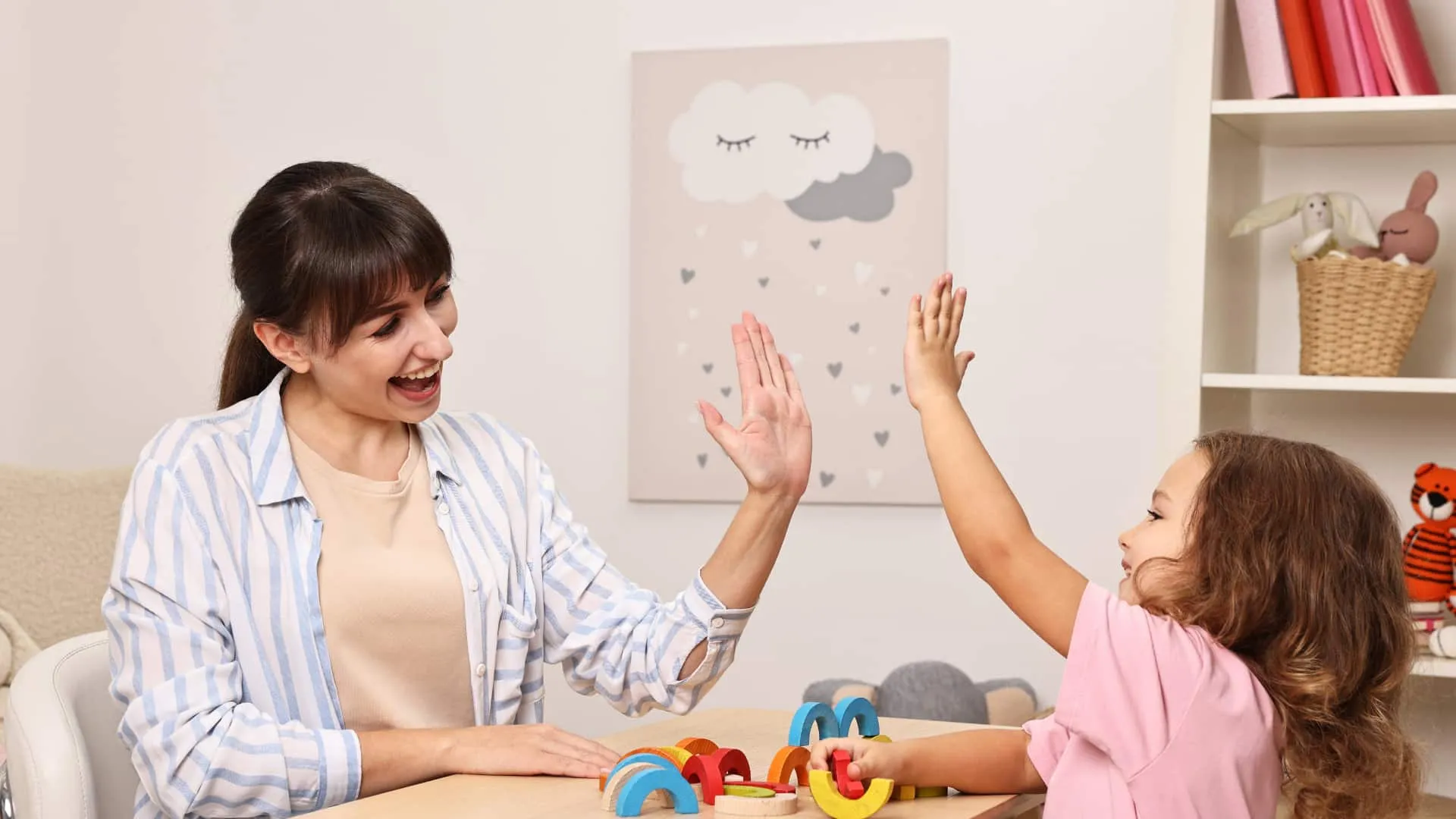 A therapist and a young child celebrate progress