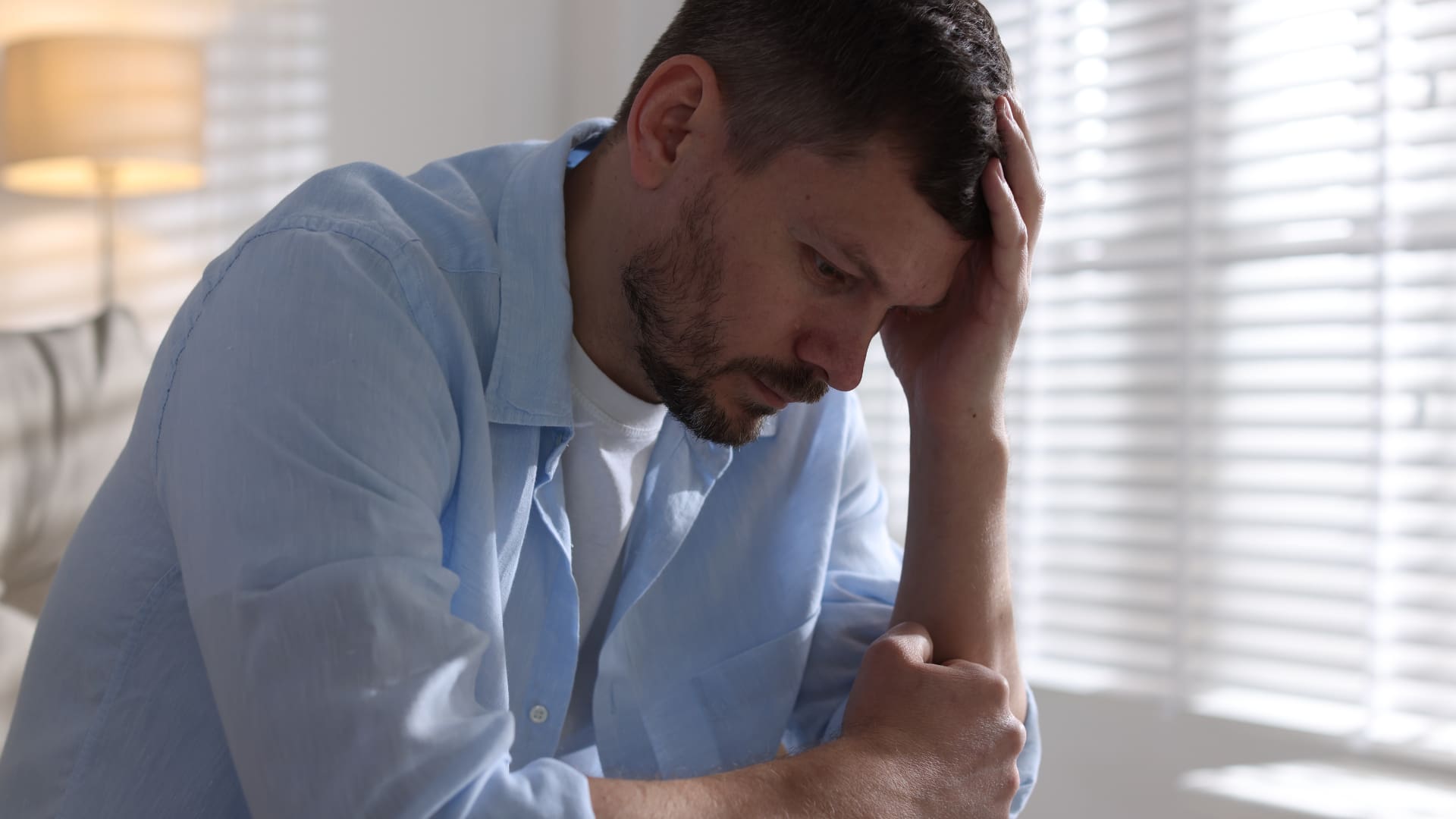 person holding his head, representing understanding and addressing mens mental health